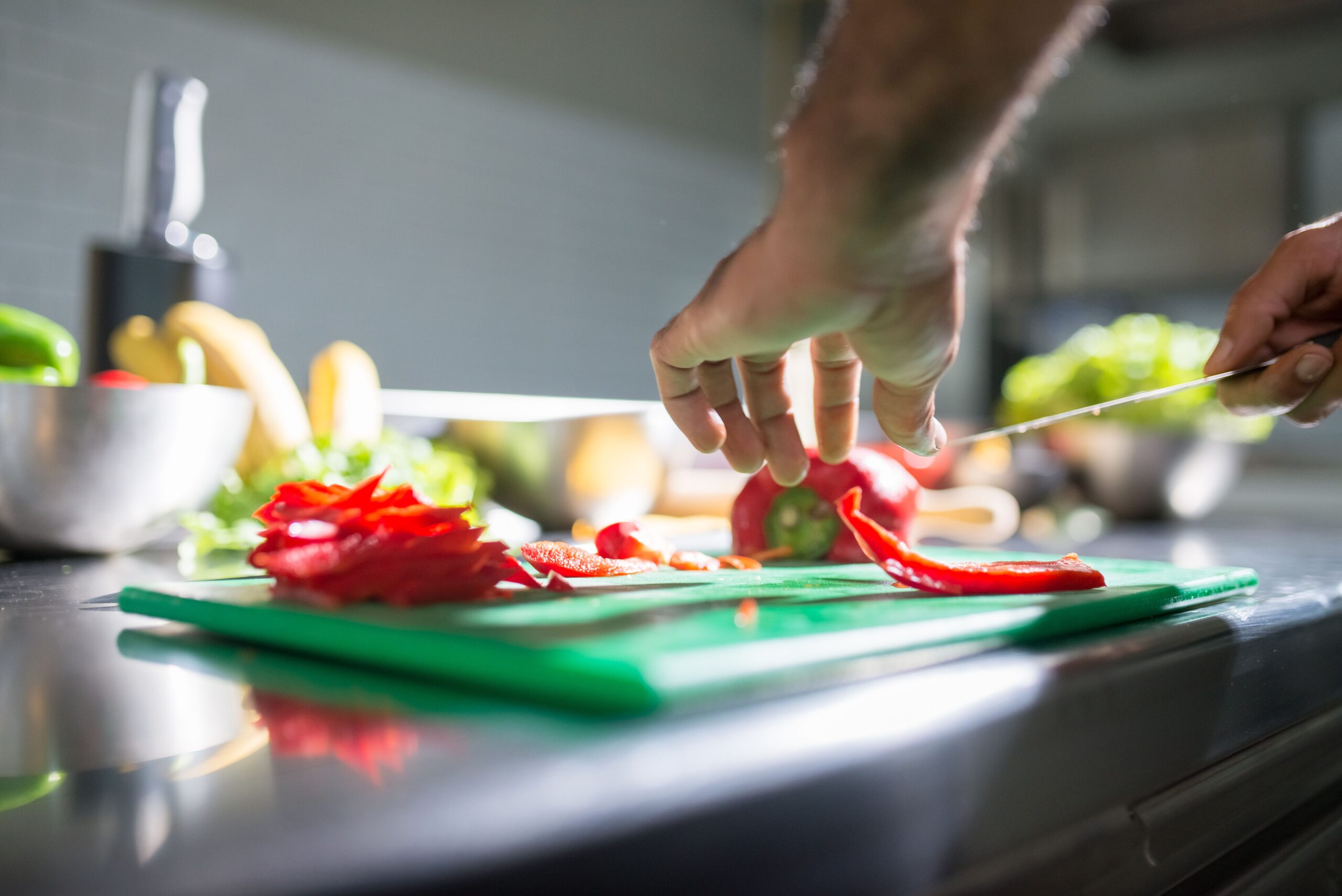 Cool kitchen gadgets: hands slicing fresh bell pepper on a chopping board